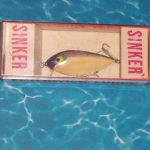 One piece cardboard box with hard plastic top. This box has a heavy paper insert indicating "Sinker" at each end.