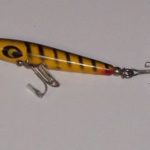 C-1000 Toothpick V3 - Devils. This is the traditional 2 3/4" long wood body. The hardware is the normal 2 hook design with a rear ball weight.
This bait is stamped Devils Toothpick. Color: #5 Yellow & Black Stripper.