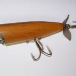 Gandy Dancer - Prototype - Modification
This lure is made of wood and comes in a clear cedar finish. It is 3" long and has a split ring on the line tie. It has the older hardware and a spinner on the rear. It has several holes in it where they tried different positions for the hardware to see how it changes the action in the water.
It is a Gandy Dancer body. It has the curved cut on the nose but they have not make the 2 final cuts on the lip to make it a Gandy Dancer.
Looks like they were trying to make a new lure from the old Gandy Dancer Perhaps the forerunner of what would become the Wood Chug.